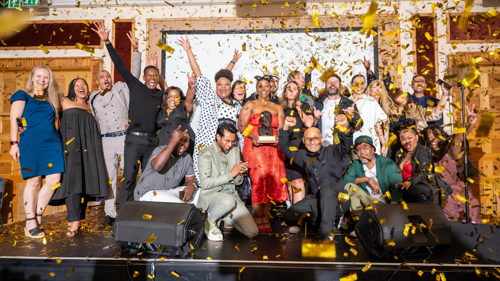 Large group of guests celebrating on stage with gold confetti at the Assegai Awards 2025